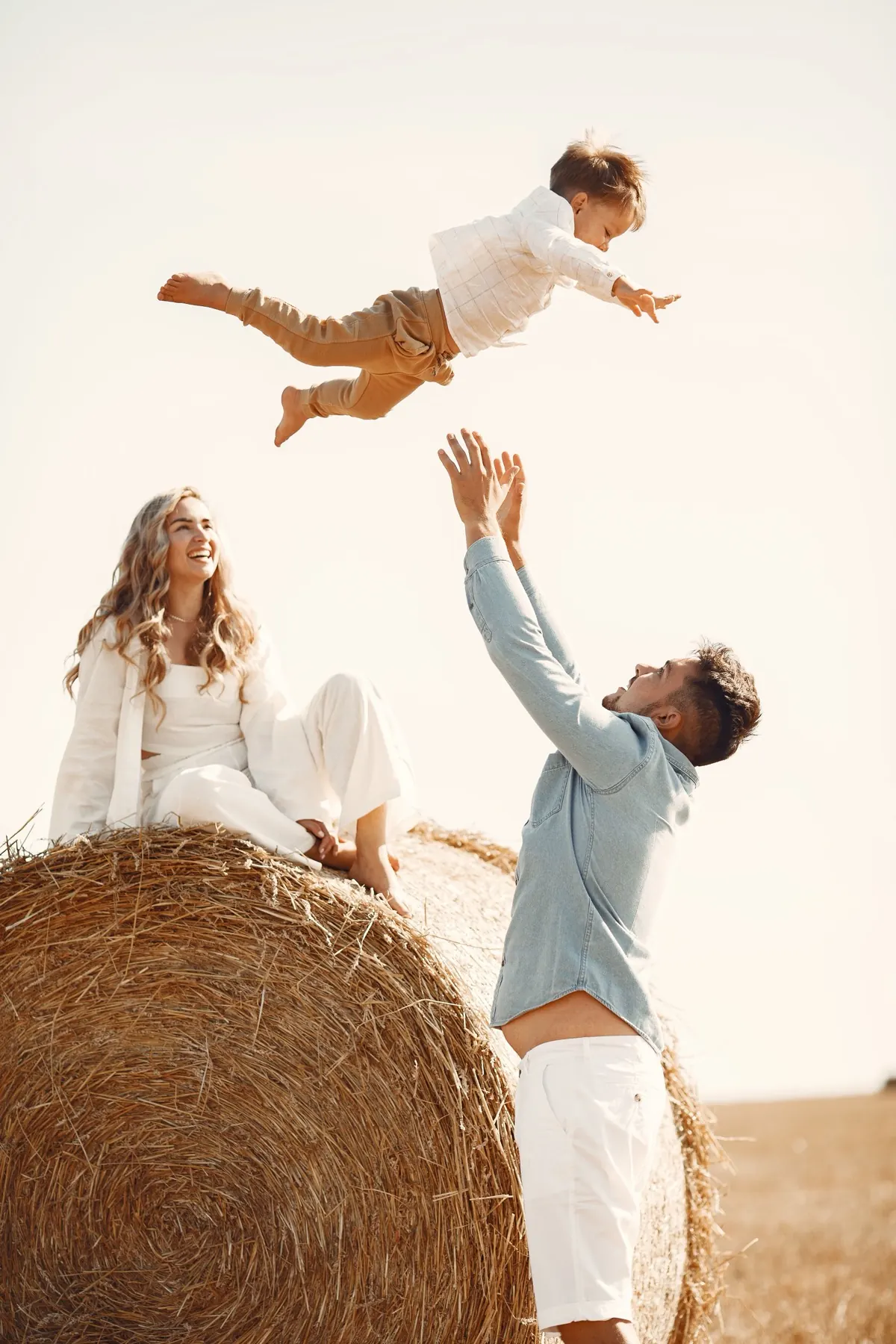 Young family playing together in a wheat field at sunset